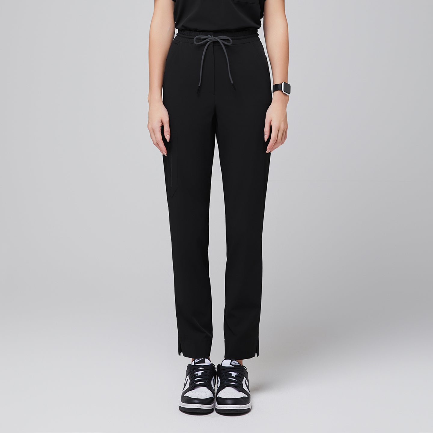 Image of Streamlined scrub pants featuring a drawstring waist, zipper pocket, and split hem, paired with casual sneakers for a professional yet relaxed look,Eco Black